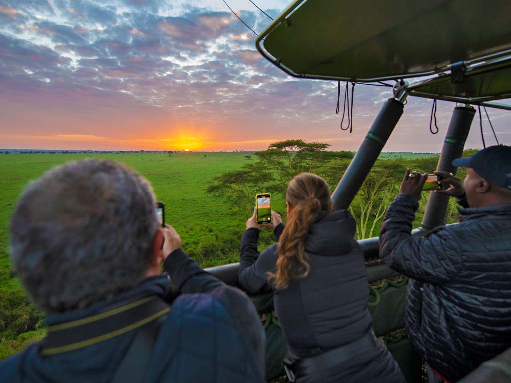 Tourists enjoying the breathtaking view of Serengeti during hot air balloon safaris.
